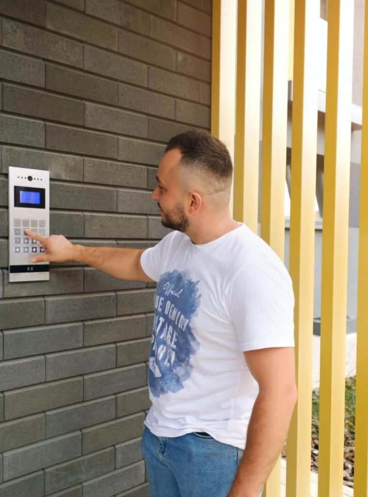 Man stands at the residential building and dials the code from the intercom door Man stands at the residential building and dials the code from the intercom door