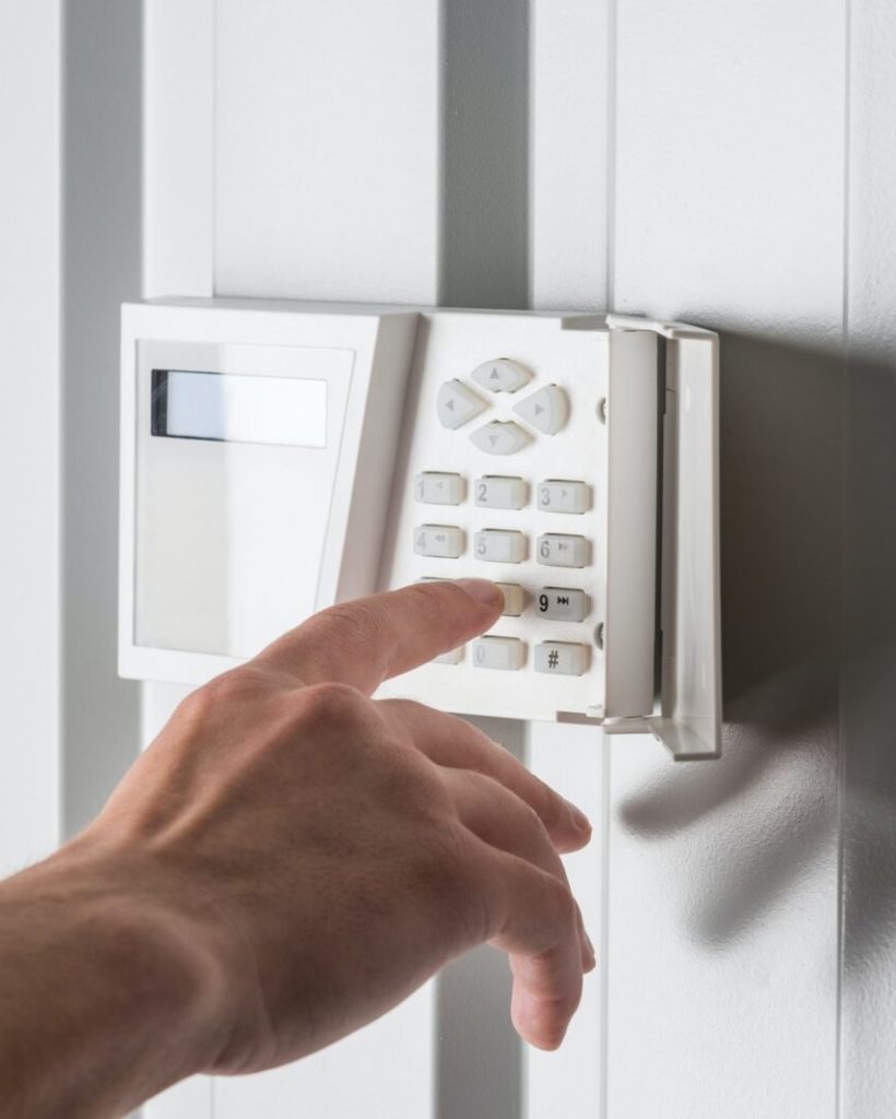 person typing on keypad of home security alarm, security system concept person typing on keypad of home security alarm, security system concept